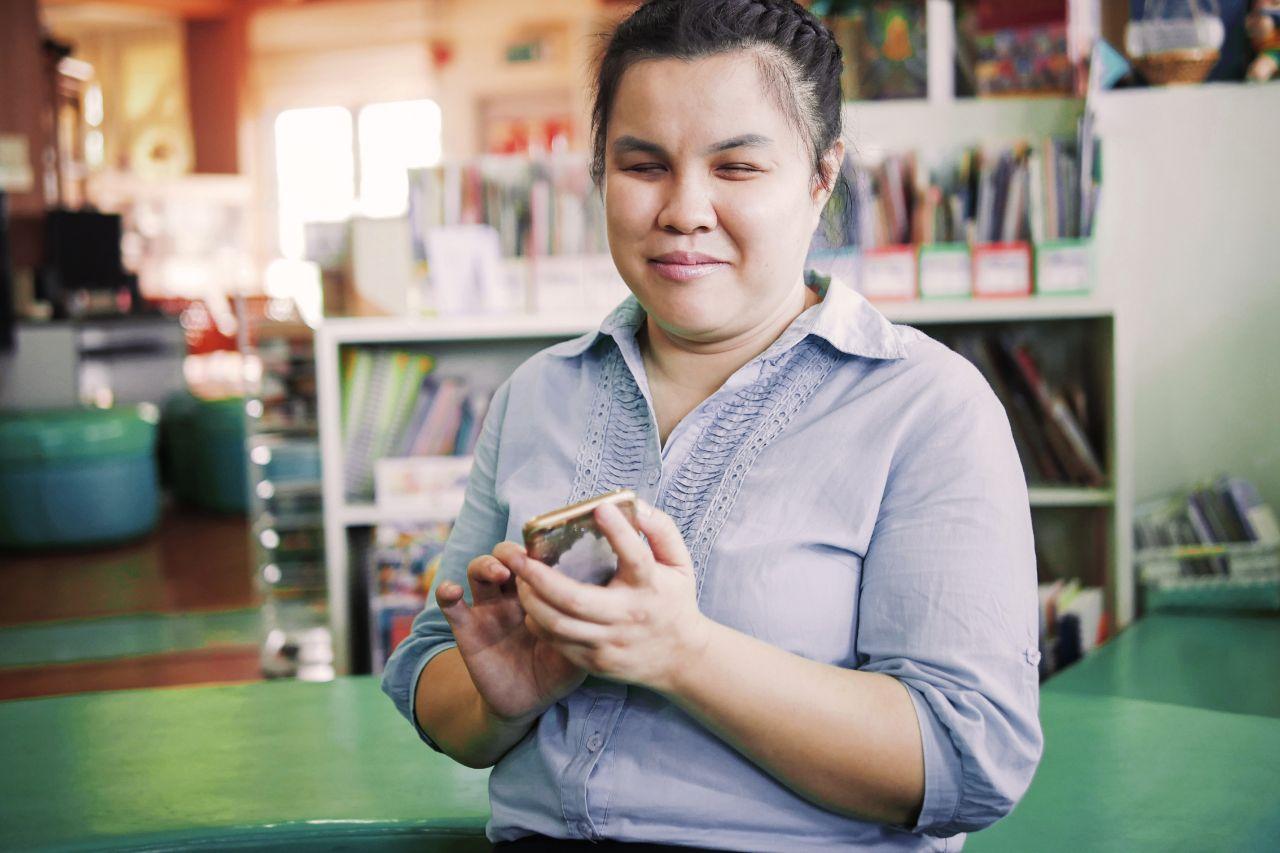 Illustrative image of a person with visual disability holding a mobile device